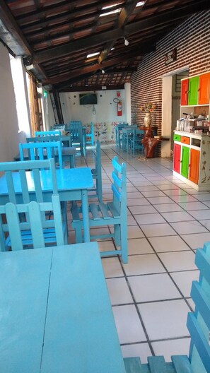A restaurant with blue tables and chairs, a brick wall, and a tiled floor.