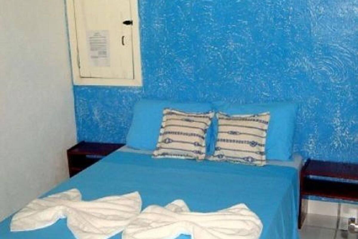 Ein Zimmer mit einer blauen Bettdecke, zwei Kissen und einem weißen Handtuch auf dem Bett.