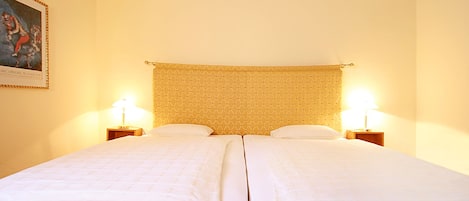 Una cama doble con cabecera, dos mesitas de noche y un cuadro en la pared.