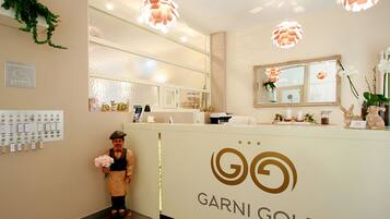 Zona de recepción con mostrador, una figura decorativa, un espejo y un cartel que dice "GARNI GOLF".
