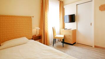 Ein Hotelzimmer mit Bett, Schreibtisch mit Stuhl, Fernseher und Kleiderschrank.