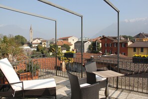 Um terraço com mobiliário de vime e vista para uma cidade com edifícios e uma igreja.