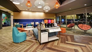 Un espacio lounge moderno con asientos, una estación de café e iluminación decorativa.