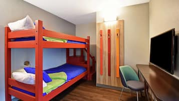 Una cama litera con escritorio y silla, un televisor y un armario en una habitación con piso de madera.