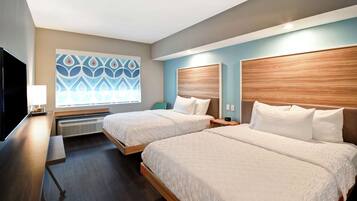 A hotel room with two beds, a desk, a TV, and a decorative wall.