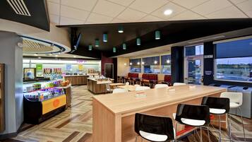 A modern cafe with a wooden counter, bar stools, and a refrigerated display.
