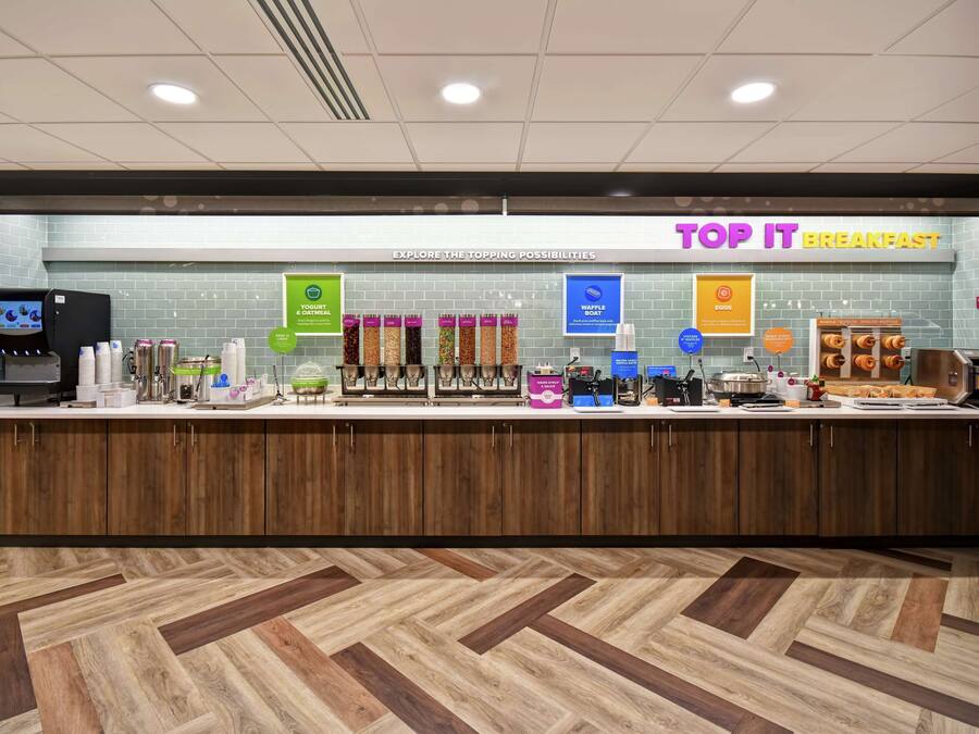A breakfast counter with a variety of food options, a coffee machine, and a waffle boat.