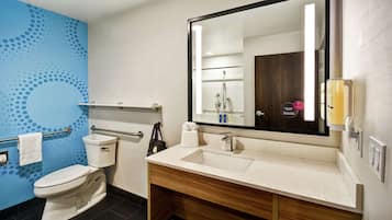 Un baño con inodoro blanco, lavamanos con espejo y pared azul con diseño de lunares.