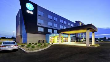 A modern hotel with a prominent 'tru' logo, a covered entrance, and a well-lit facade.