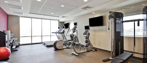 A gym with treadmills, elliptical machines, and a weight bench.
