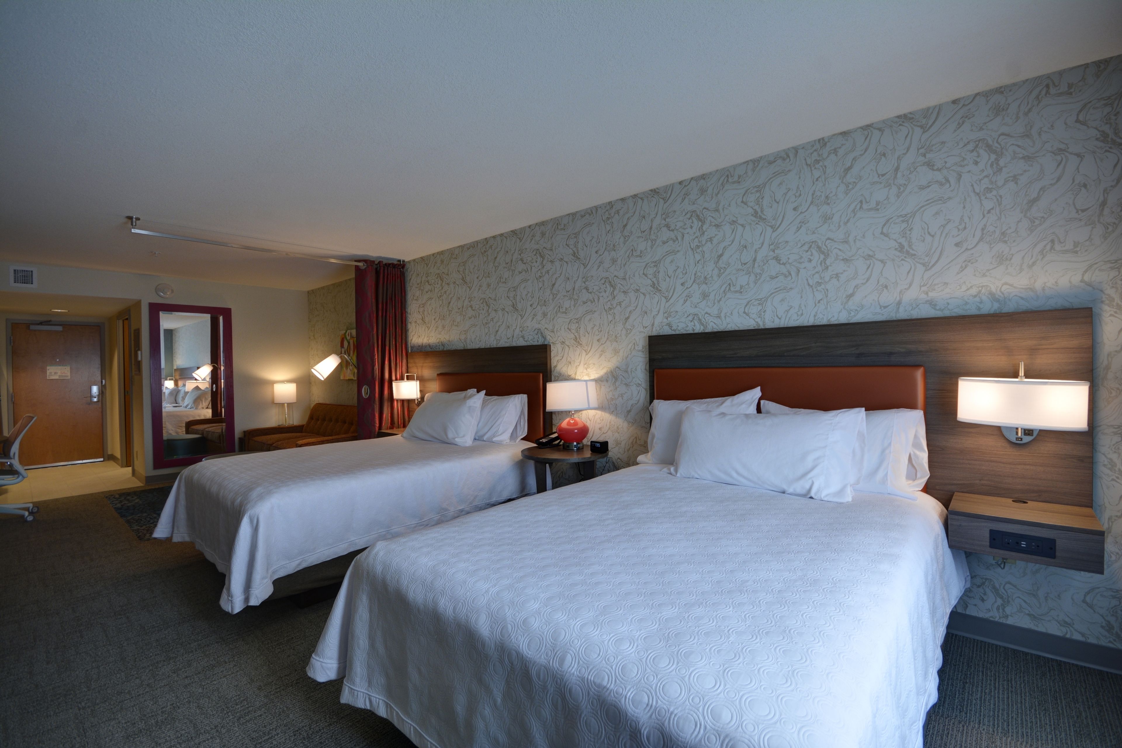 Une chambre d’hôtel avec deux lits, un bureau et une chaise.