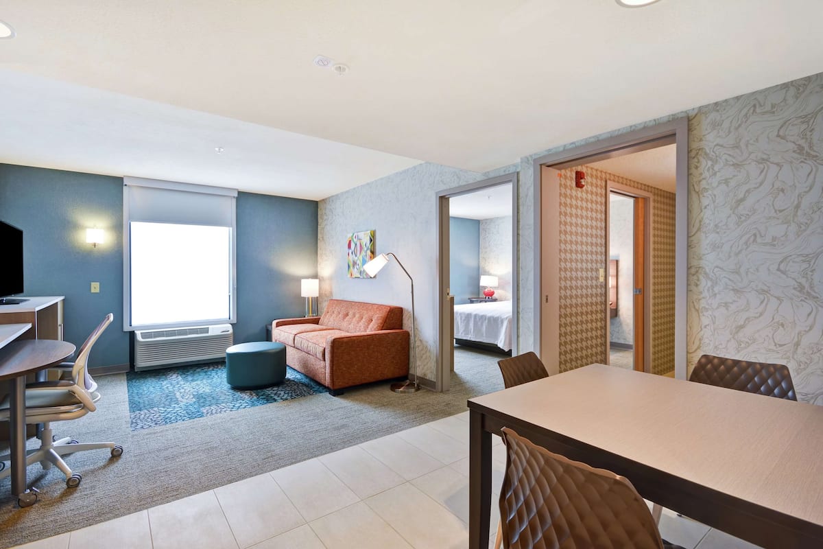 Ett hotellrum med ett skrivbord, en soffa, ett matbord och en säng.