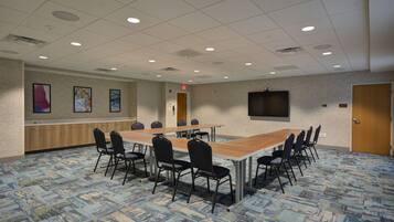 A conference room with a long table, chairs, a TV, and artwork on the wall.