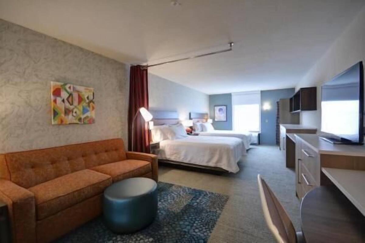 Ett hotellrum med en soffa, en säng, en TV och ett skrivbord.