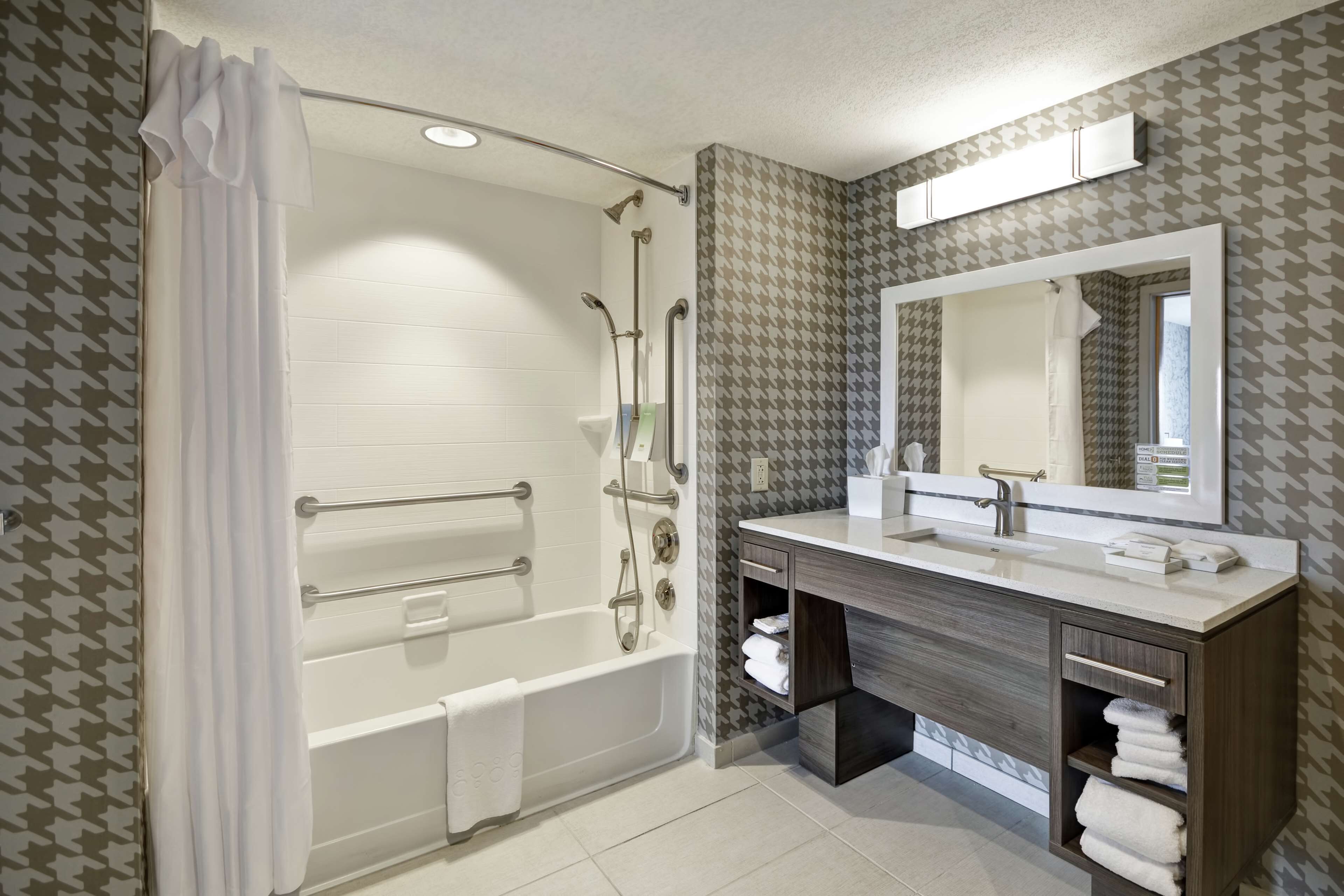 Un baño con bañera, ducha, tocador con espejo y espacio para toallas.