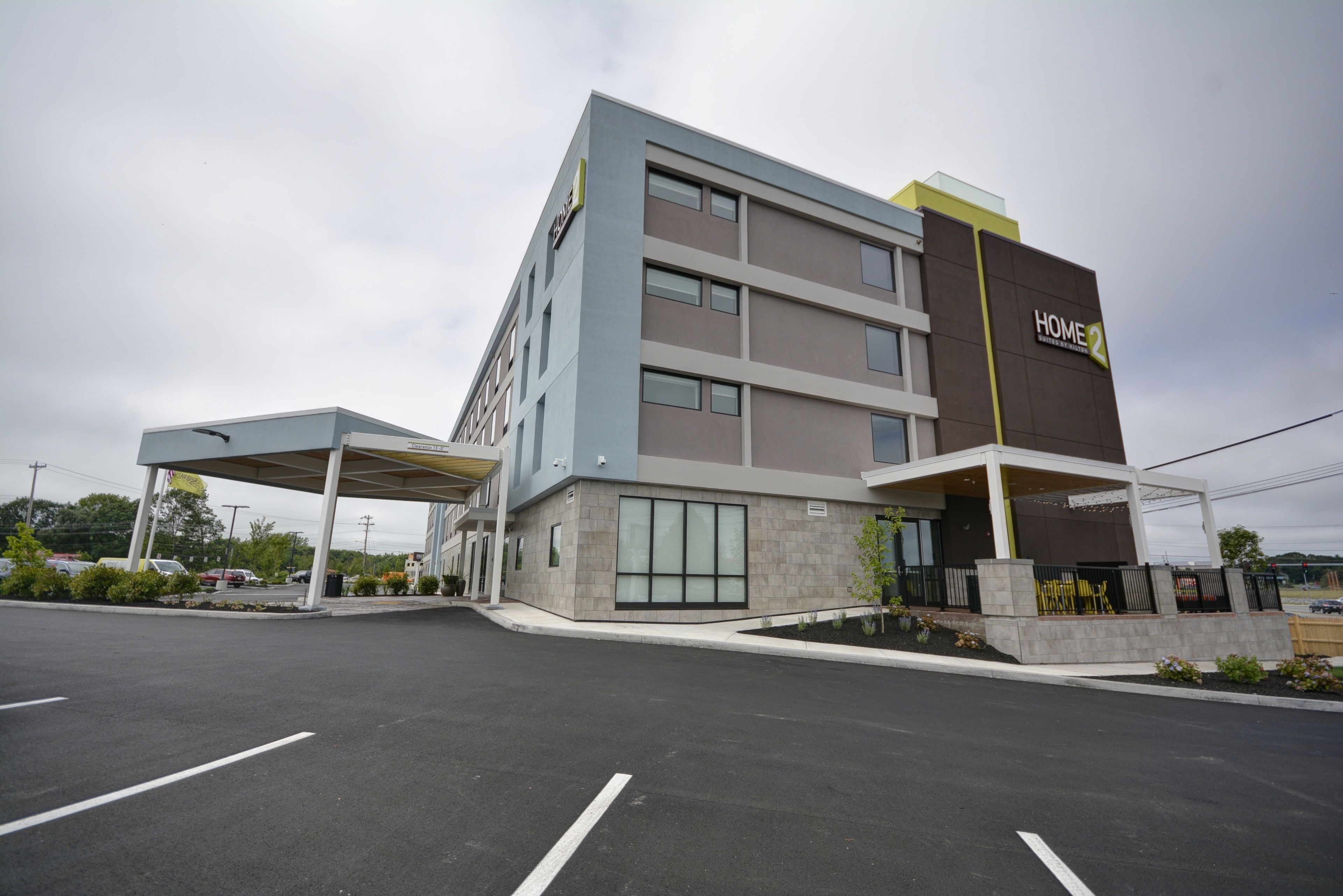 A multi-story hotel with a modern design, featuring a covered parking area and a prominent "HOME 2" sign.