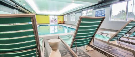 A pool area with lounge chairs and a lifeguard sign.
