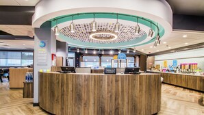 Una moderna zona de recepción de hotel con un mostrador de madera, un aplique de techo circular y un cartel visible de Hilton Honors.