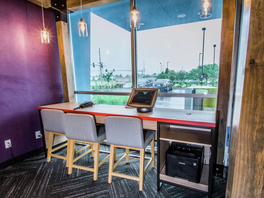 A modern office space with a desk, two chairs, a computer, and a view of the outside.