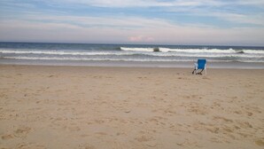 Une plage avec une seule chaise longue bleue et des empreintes de pas dans le sable.