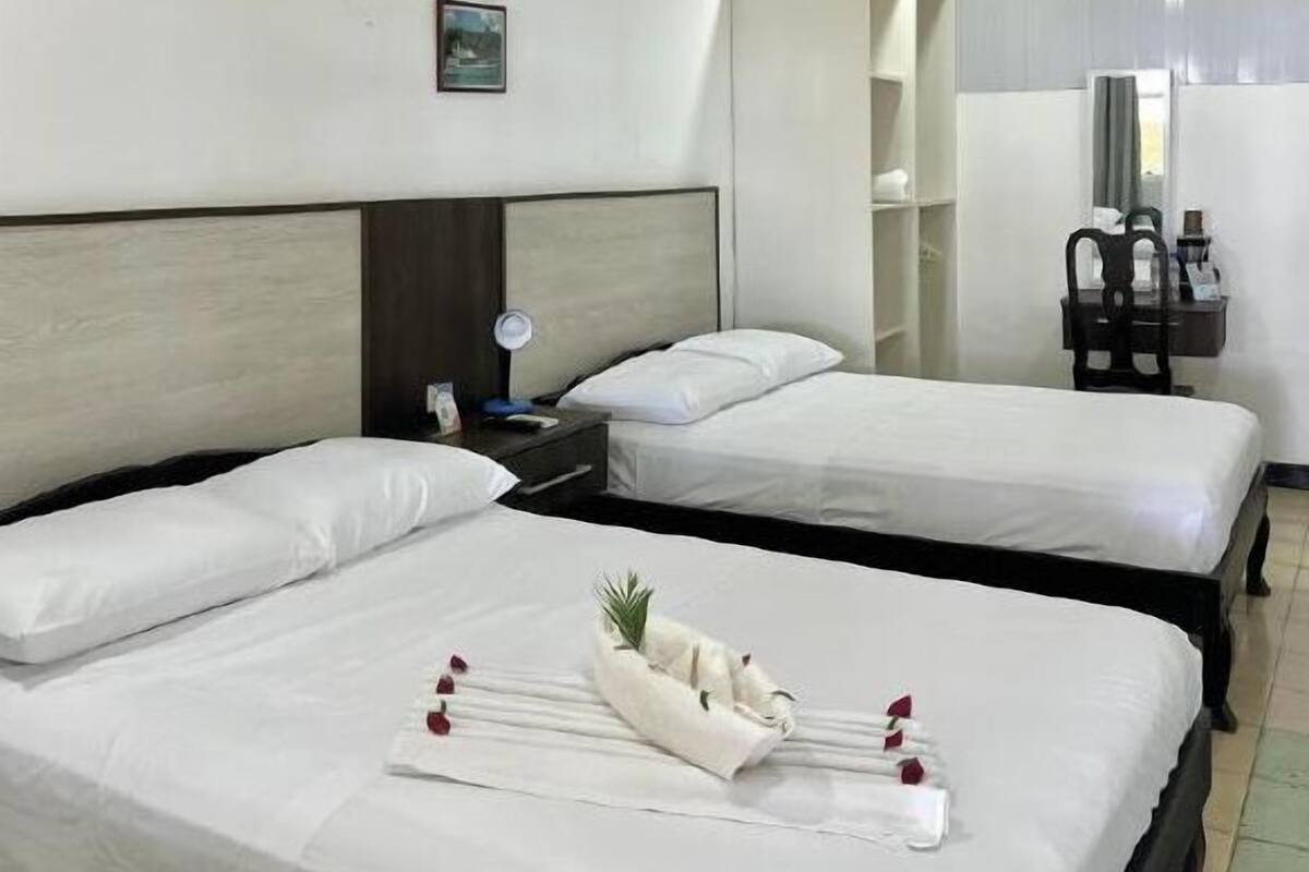 A hotel room with two beds, a nightstand, a mirror, and a wardrobe.