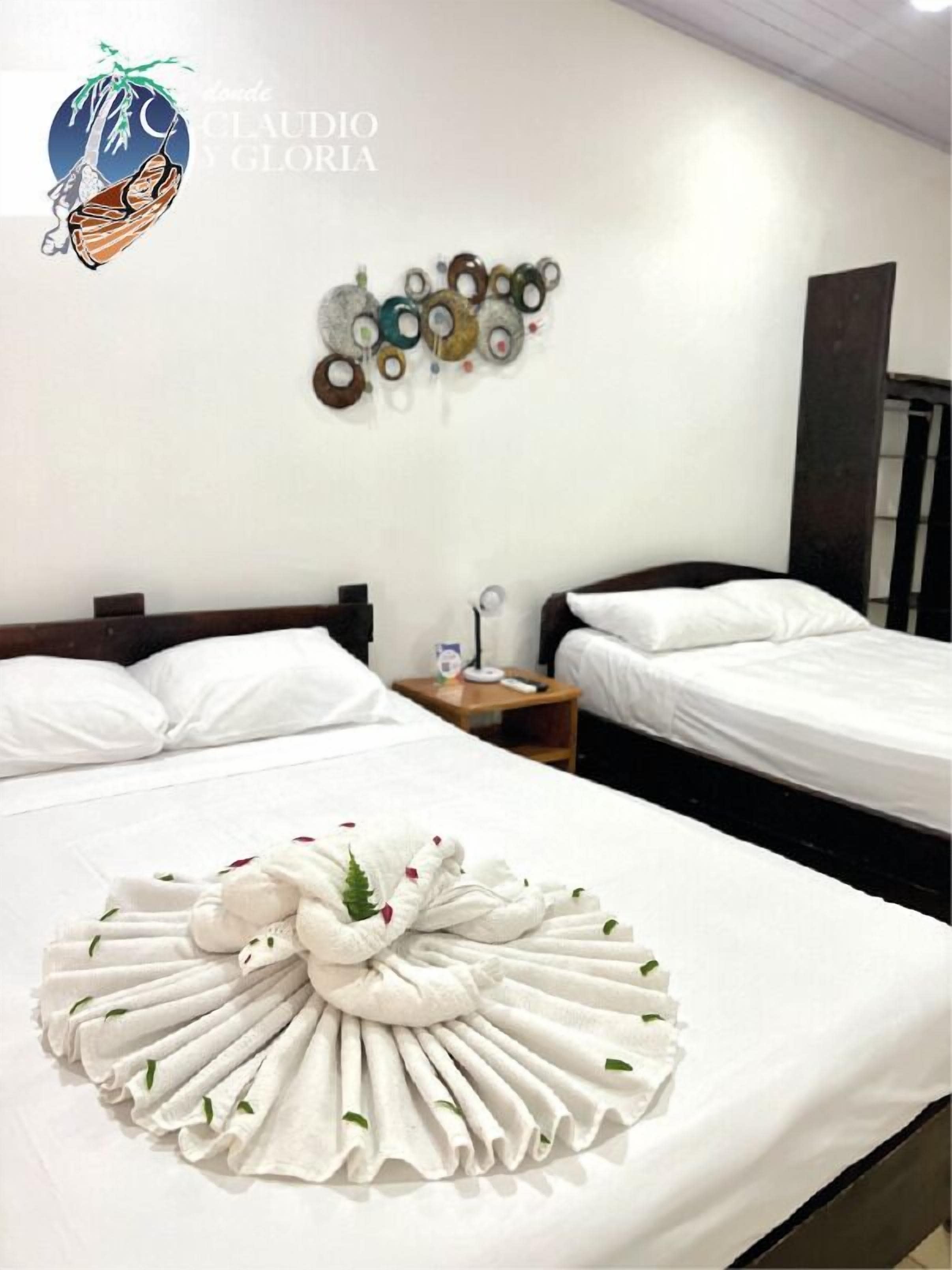 A hotel room with two beds, a wall art piece, and a towel art arrangement on the bed.