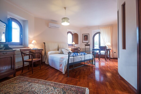 A bedroom with a bed, bedside tables, a desk, a chair, and a window.