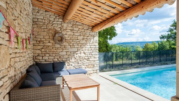A covered outdoor seating area with stone walls, a pool, and a view of the countryside. - Villa in Saignon with Pool and Scenic Views (Saignon)