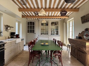 A kitchen with a green table, wooden chairs, a hanging light fixture, and a cabinet with glass doors. - Villa in Saignon with Pool and Scenic Views (Saignon)