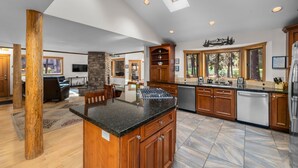 A spacious kitchen with a central island, wooden cabinets, and a stone fireplace.