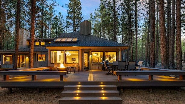A modern cabin with a deck, built-in seating, and a fireplace.