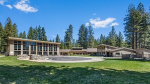 A modern building with a central courtyard, surrounded by a well-maintained lawn and tall trees.