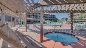 Zona de piscina amb banyera d'hidromassatge, gandules i una estructura de pergola de fusta.