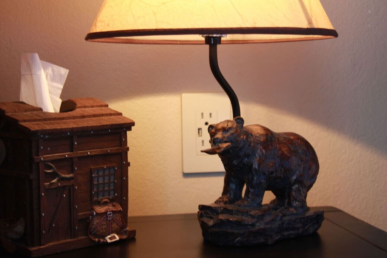 Une lampe sur une table, surmontée d’une statuette d’ours.