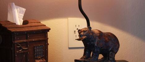 Une lampe sur une table, surmontée d’une statuette d’ours.