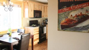 A kitchen with wooden cabinets, a black microwave, and a dining area with a table and chairs.