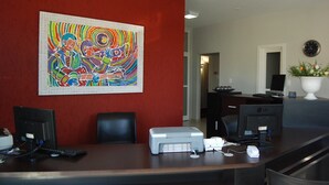A reception desk with a large abstract painting, a printer, and a computer monitor. - Hotel Recanto dos Ipês (Frutal)