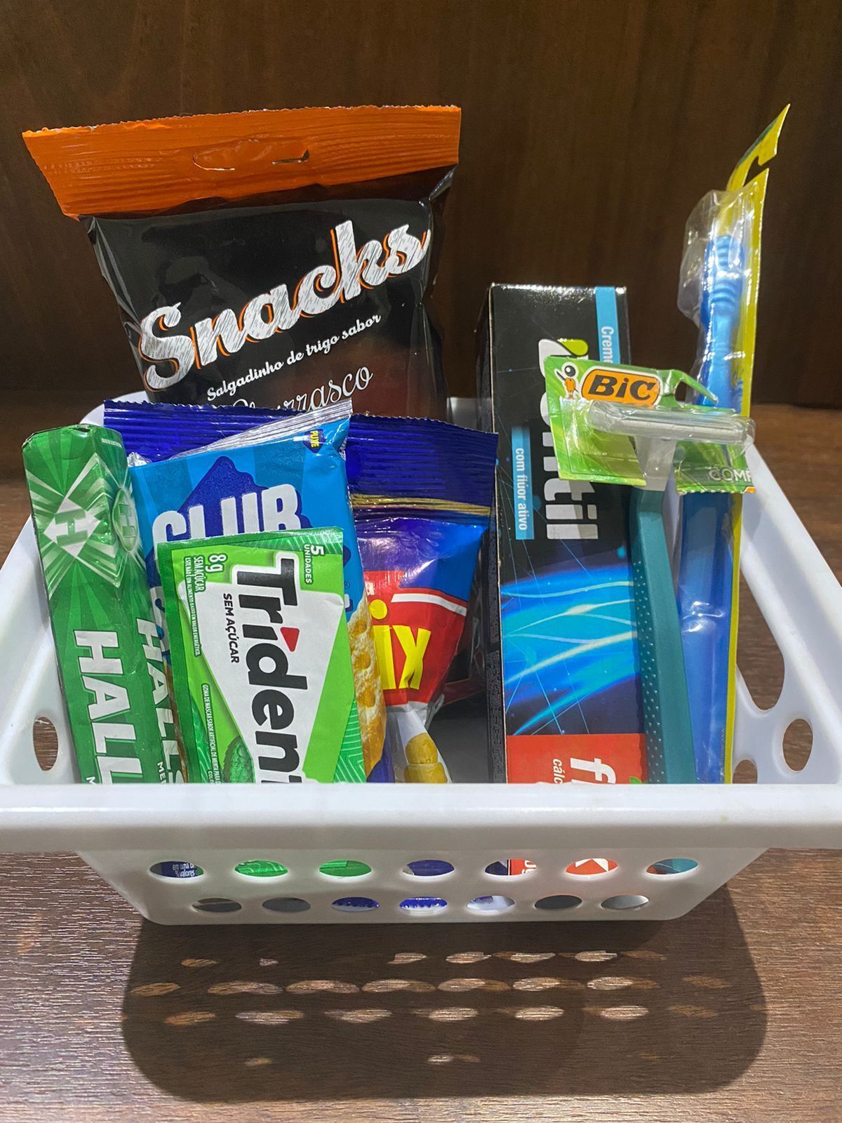 Una cesta con aperitivos, un cepillo de dientes y varios alimentos envasados.