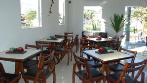 A restaurant with multiple tables and chairs, large windows, and a view of the outside. - Hotel Recanto dos Ipês (Frutal)
