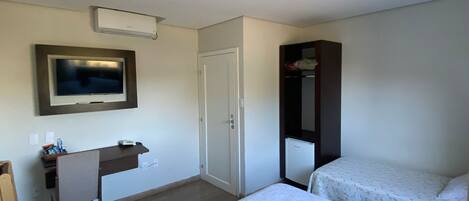 A hotel room with two beds, a desk, a TV, and a wardrobe.