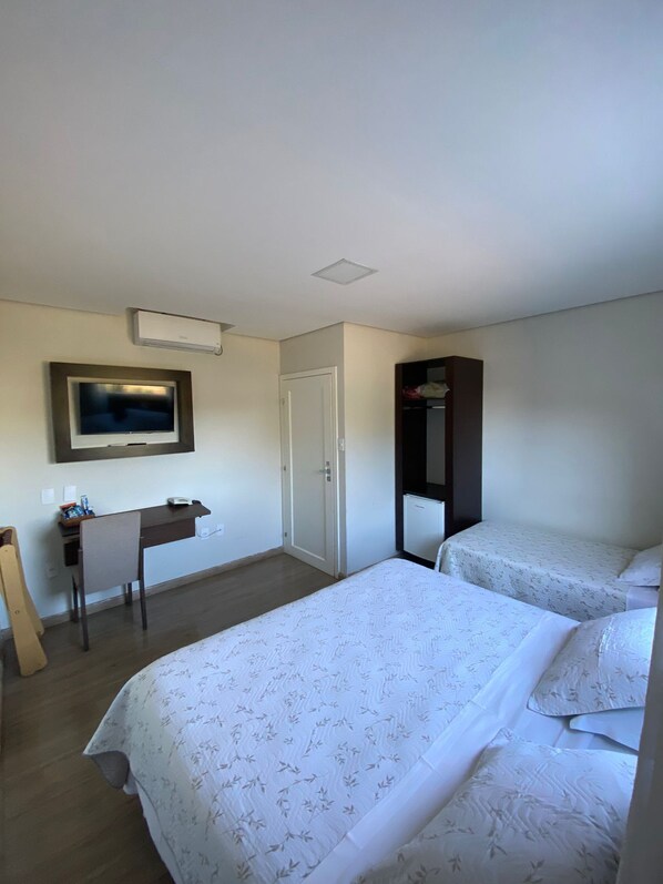 A hotel room with two beds, a desk, a TV, and a wardrobe.