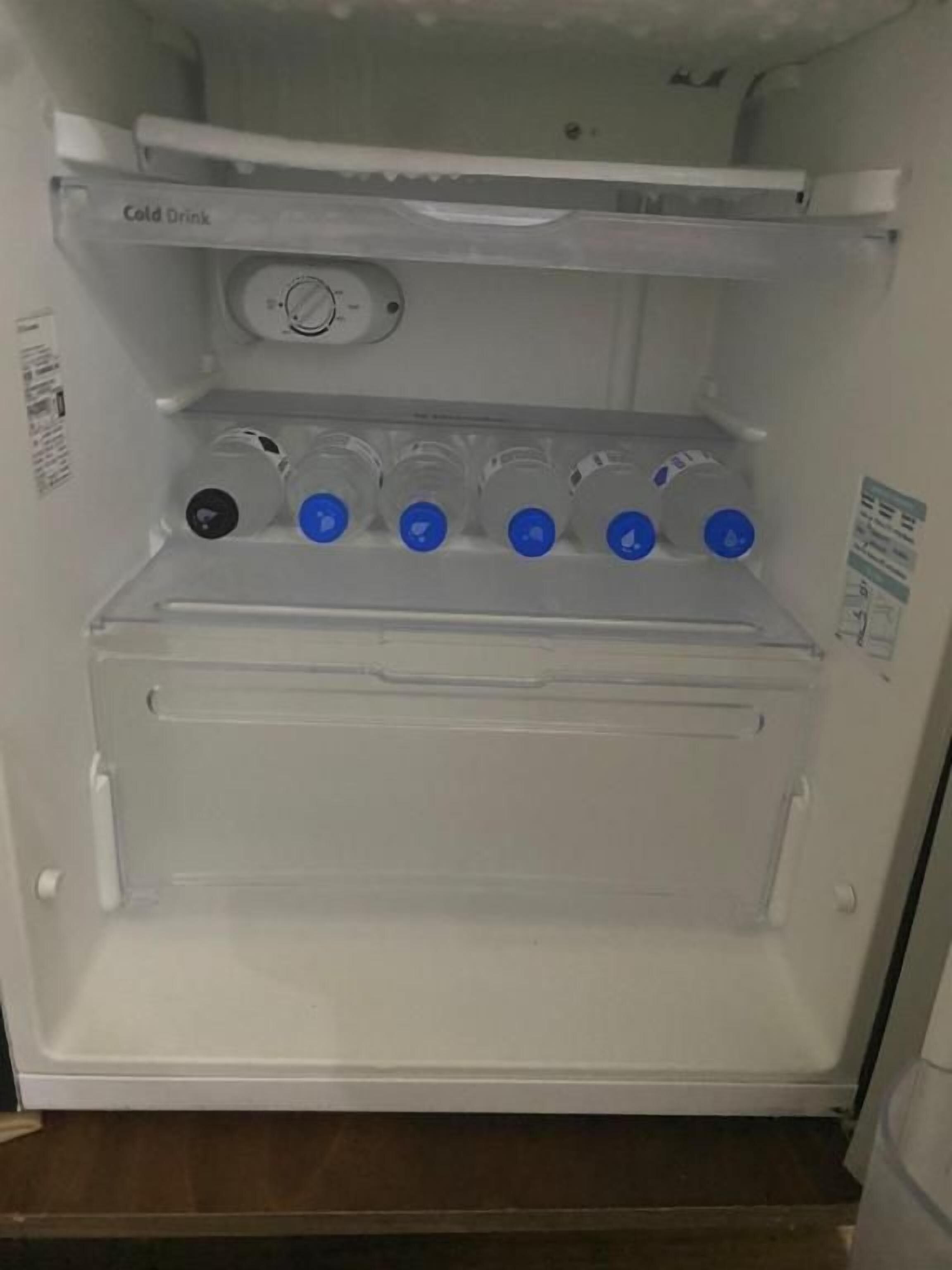 An open refrigerator with a cold drink section, a water dispenser, and a freezer compartment.