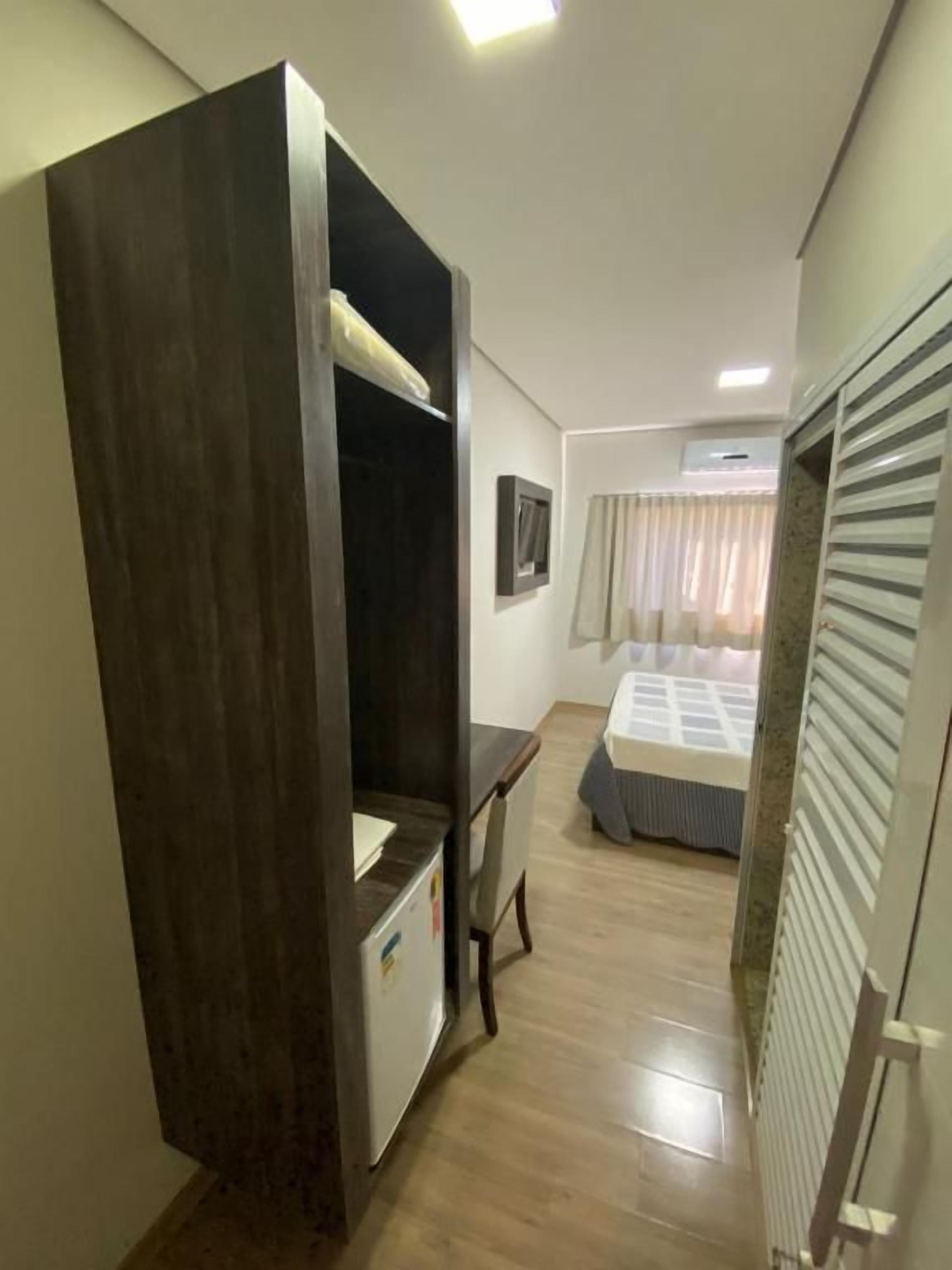 Una habitación de hotel pequeña con cama, escritorio y armario.