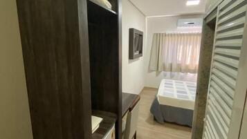 Una habitación de hotel pequeña con cama, escritorio y armario.