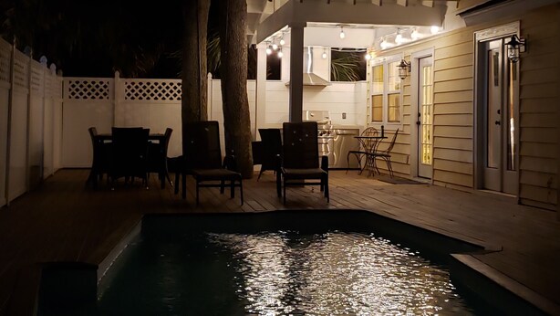 Un espace extérieur aménagé avec une terrasse, une piscine, des chaises et une table à manger.