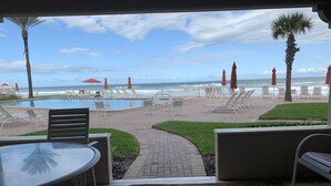 A poolside area with lounge chairs and umbrellas, a pathway leading to the beach, and a view of the ocean. - Ground floor with King master, 2 twins 2nd bedroom Bunk beds in 3rd bedroom (twins) twin/full combo. (New Smyrna Beach)