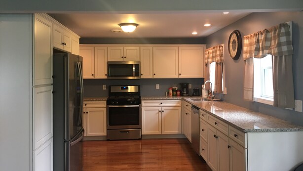 A modern kitchen with white cabinets, stainless steel appliances, and a granite countertop. - Watkins Glen lake view rental (Watkins Glen)