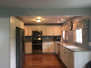 A modern kitchen with white cabinets, stainless steel appliances, and a granite countertop. - Watkins Glen lake view rental (Watkins Glen)