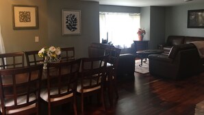 A dining area with wooden chairs and a table, a living room with a sofa and a coffee table, and a window with natural light. - Watkins Glen lake view rental (Watkins Glen)