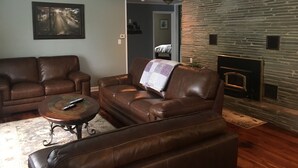 A living room with leather sofas, a coffee table, and a fireplace. - Watkins Glen lake view rental (Watkins Glen)